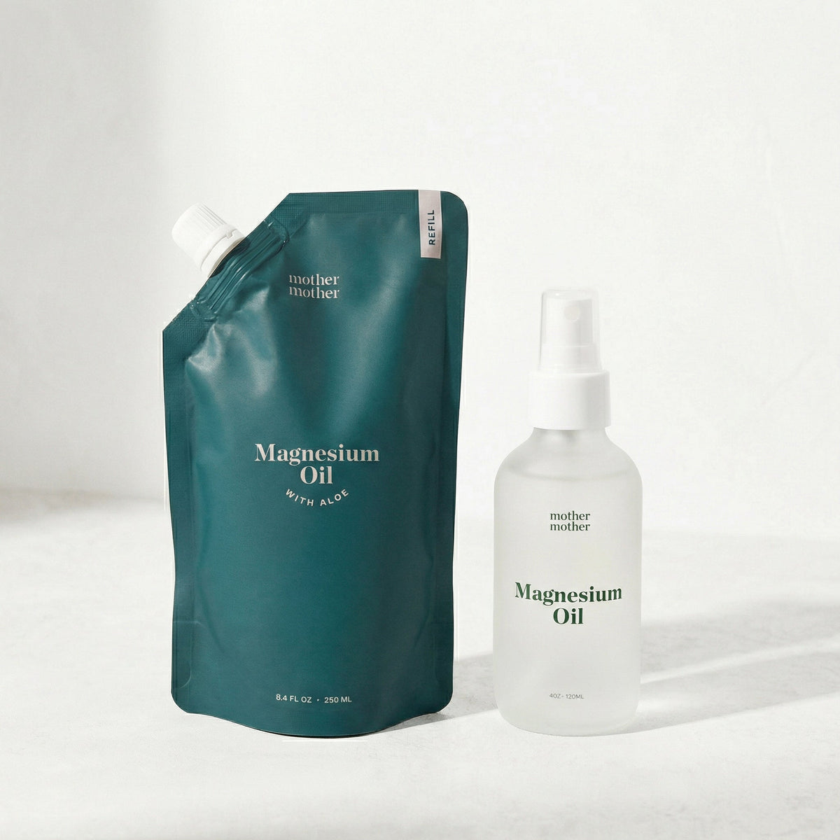 Magnesium refill pouch and glass bottle of magnesium oil with 'mother mother' branding on a light background