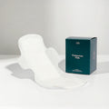 Box of postpartum pads on a white surface with a gray background