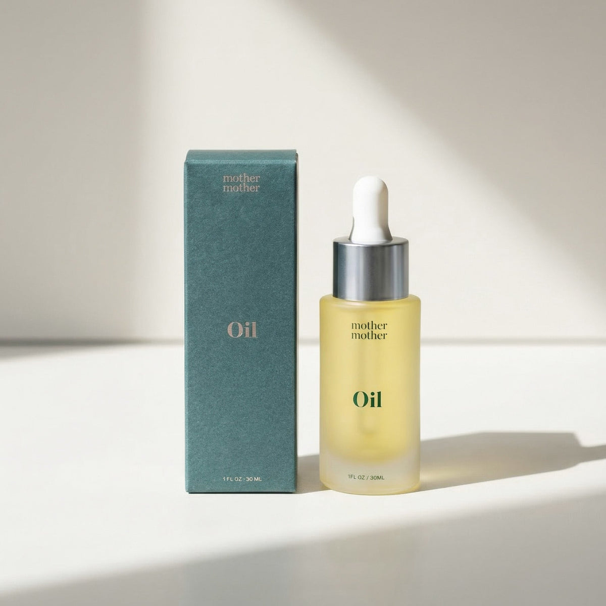 Bottle of 'mother mother' oil with dropper and packaging on a light background