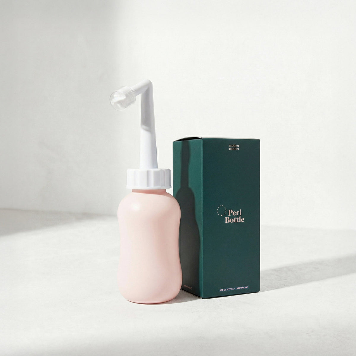 Pink peri bottle with white nozzle and green box labeled 'Peri Bottle' on a light gray background