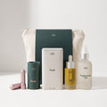 Collection of skincare products including bottles and a pouch on a light background